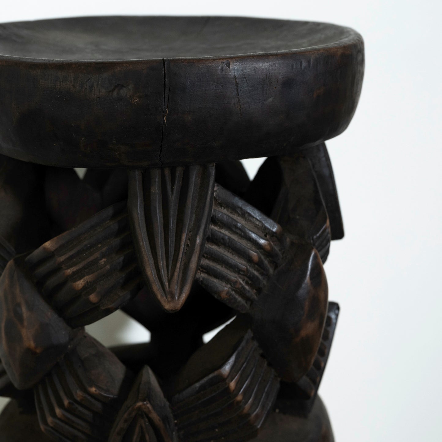 Dark wooden stool with intricate carvings on a white background