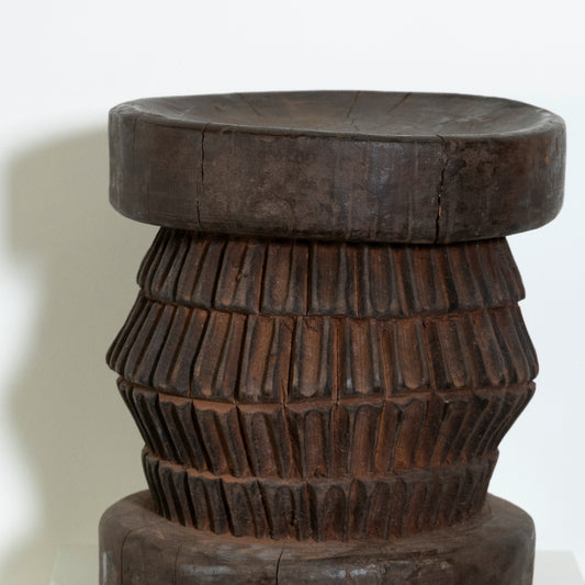 Wooden stool with a textured design on a white background