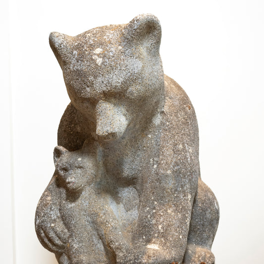 Stone sculpture of a mother bear with her cub on a white background