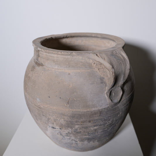 A weathered gray clay pot from 19th century central europe with rounded body two curved handles and horizontal ridges
