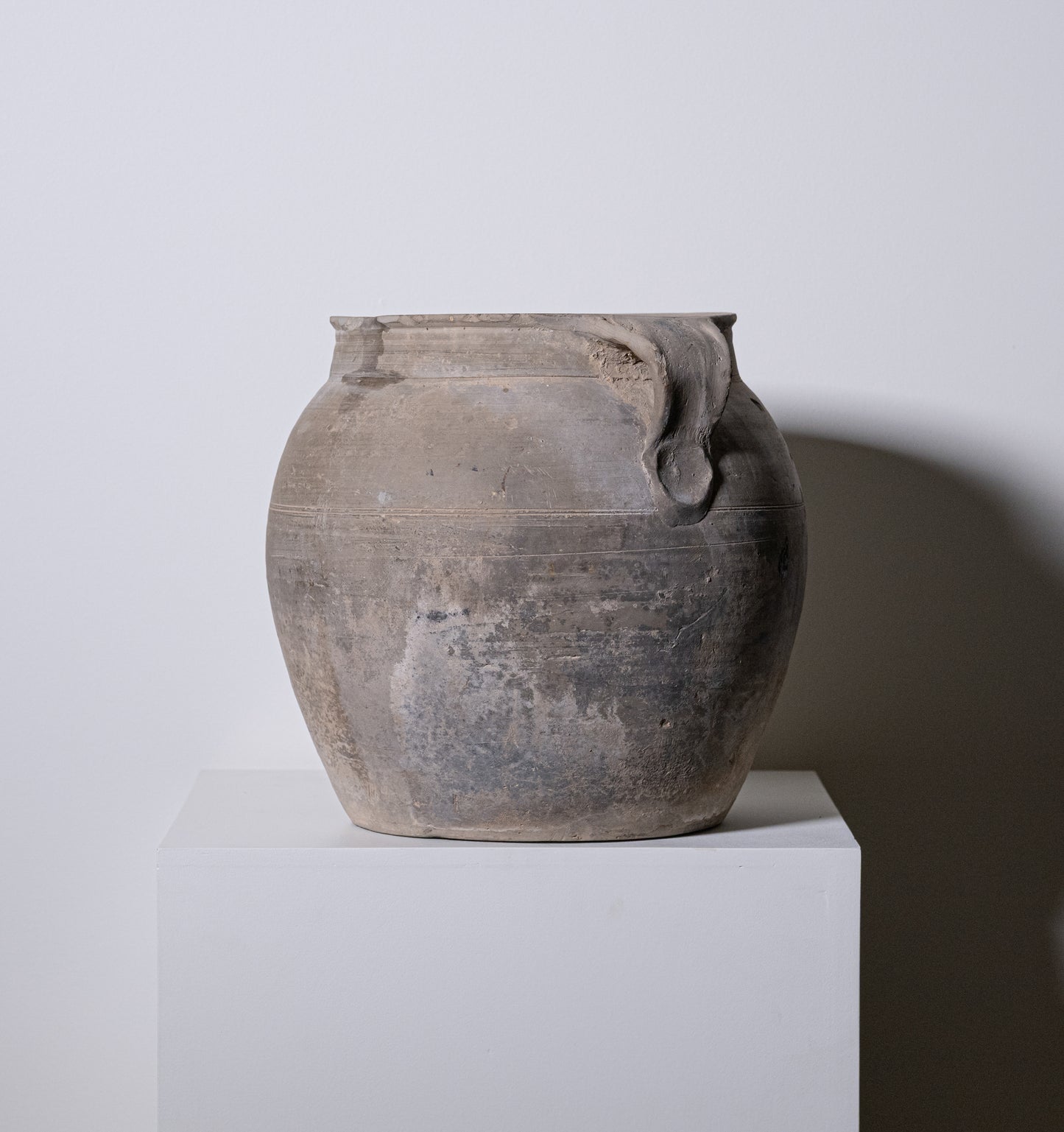 A weathered gray 19th century central european clay pot with rounded body two handles and subtle horizontal ridges