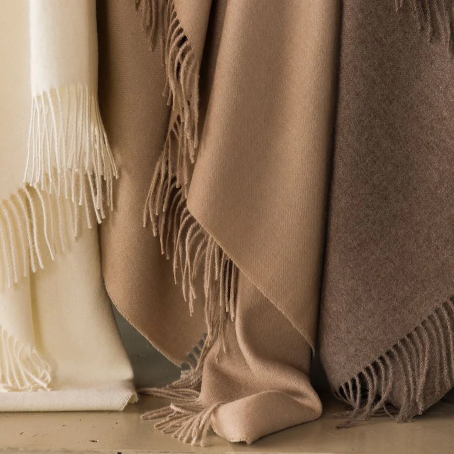 Three soft alpaca plaid throws in cream beige and taupe wool with matching fringed edges for cozy warmth