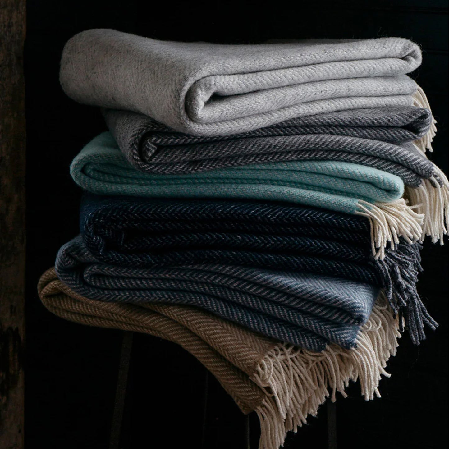 Stack of folded blankets in various colors on a dark background