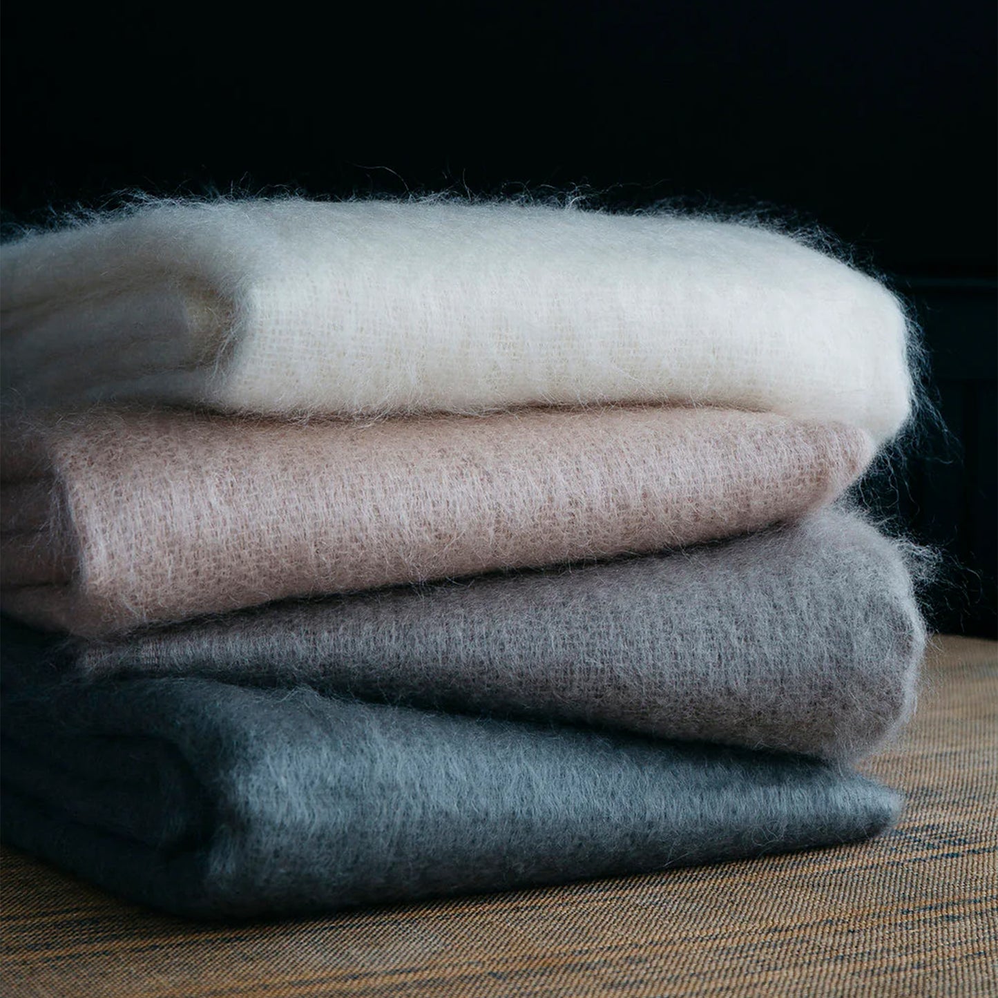 Stack of four soft fluffy mohair scarves in neutral tones including off-white blush pink gray and charcoal for cozy wear