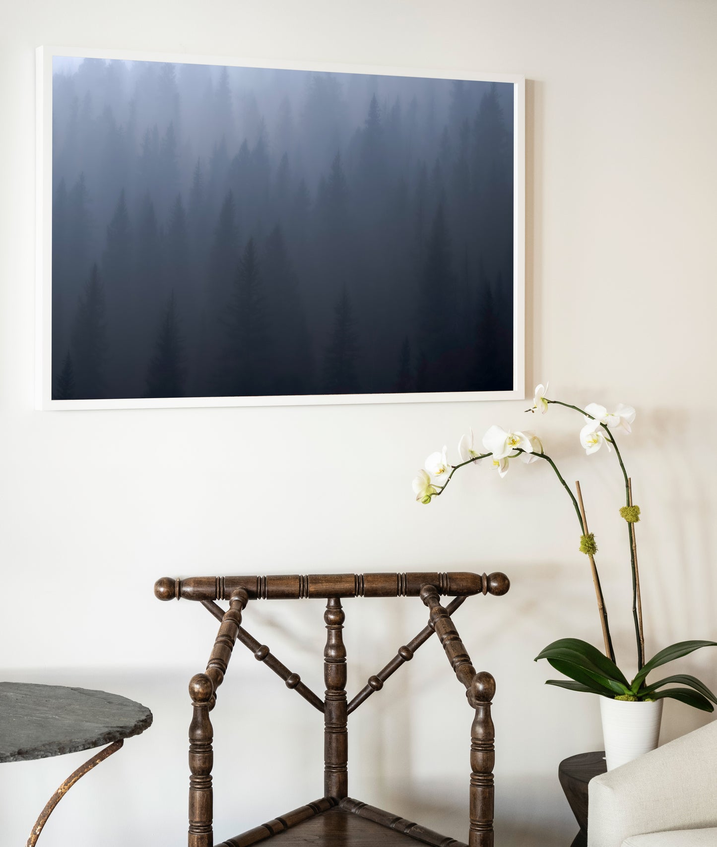 A framed photographic print titled ghost of day break featuring a misty forest in deep blues and grays in a white frame