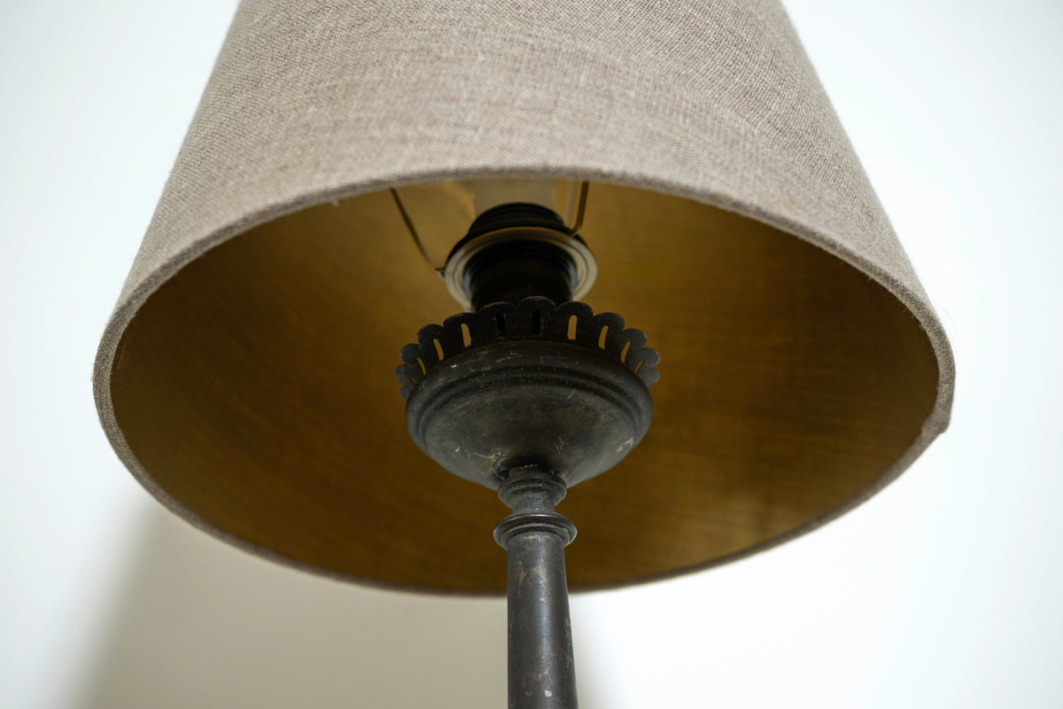 Close-up of a lamp with a beige shade and black metal base.