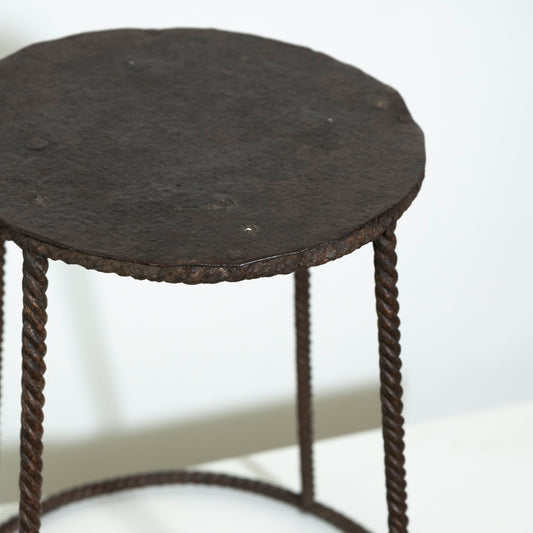 Small round table with a dark surface and rope-like legs on a white background