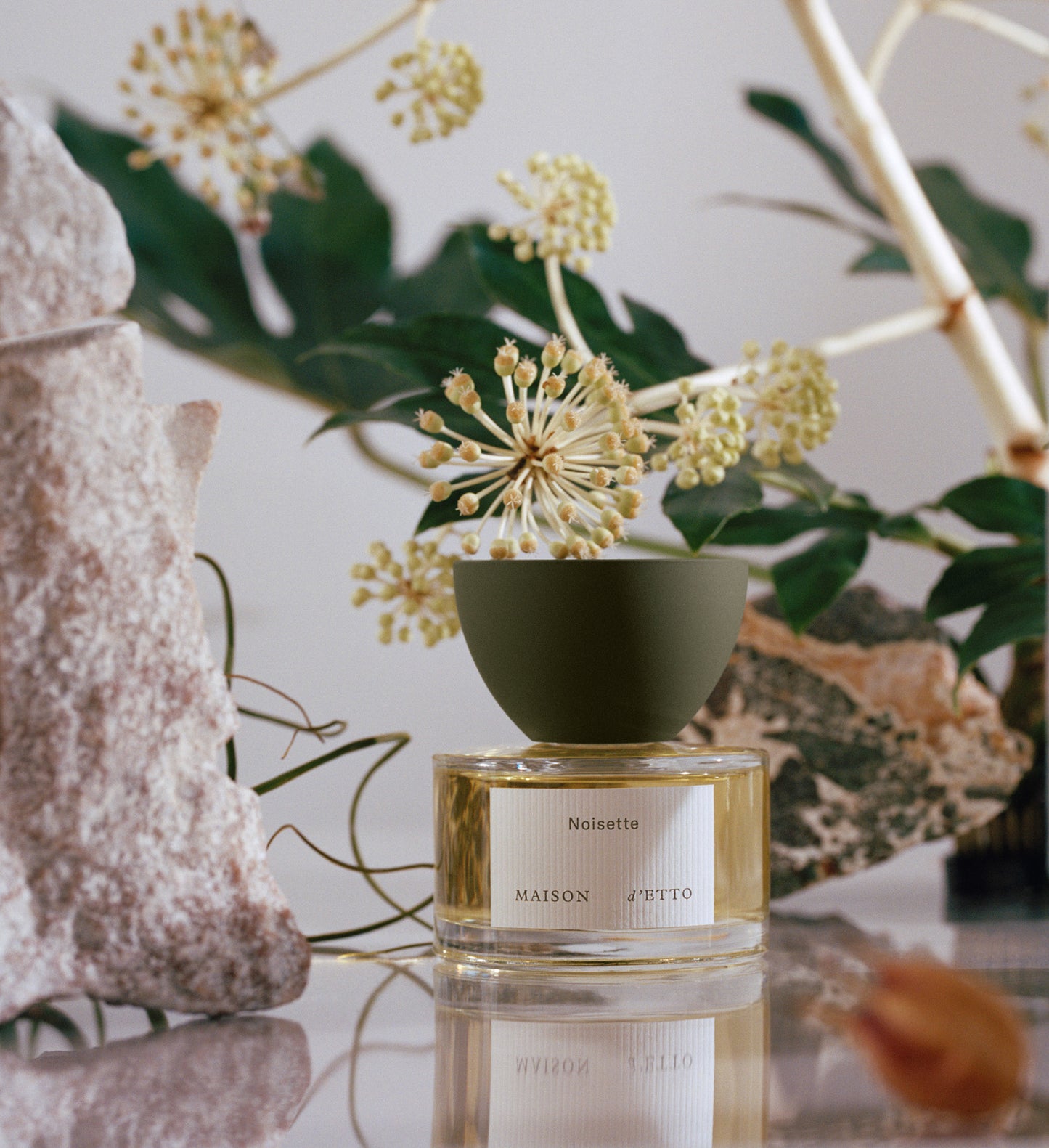 A sleek olive green ceramic diffuser with a clear glass base containing golden liquid labeled noisette by Maison d Etto
