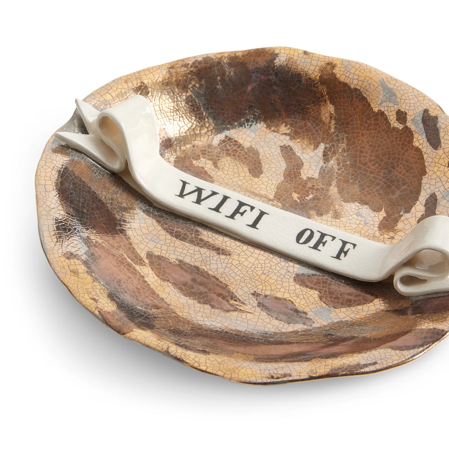 A ceramic ashtray with crackled gold and brown glaze and off-white wifi off ribbon by Ruan Hoffman