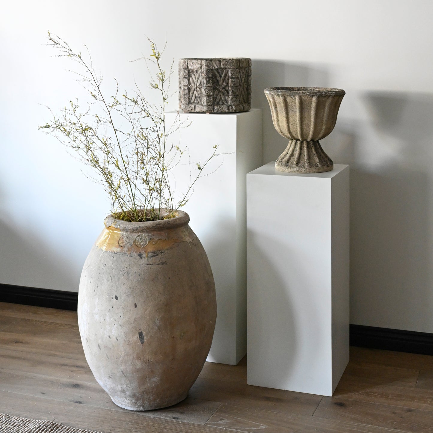 A weathered beige 20th century French fluted concrete garden urn with a flared rim and subtle gold accents