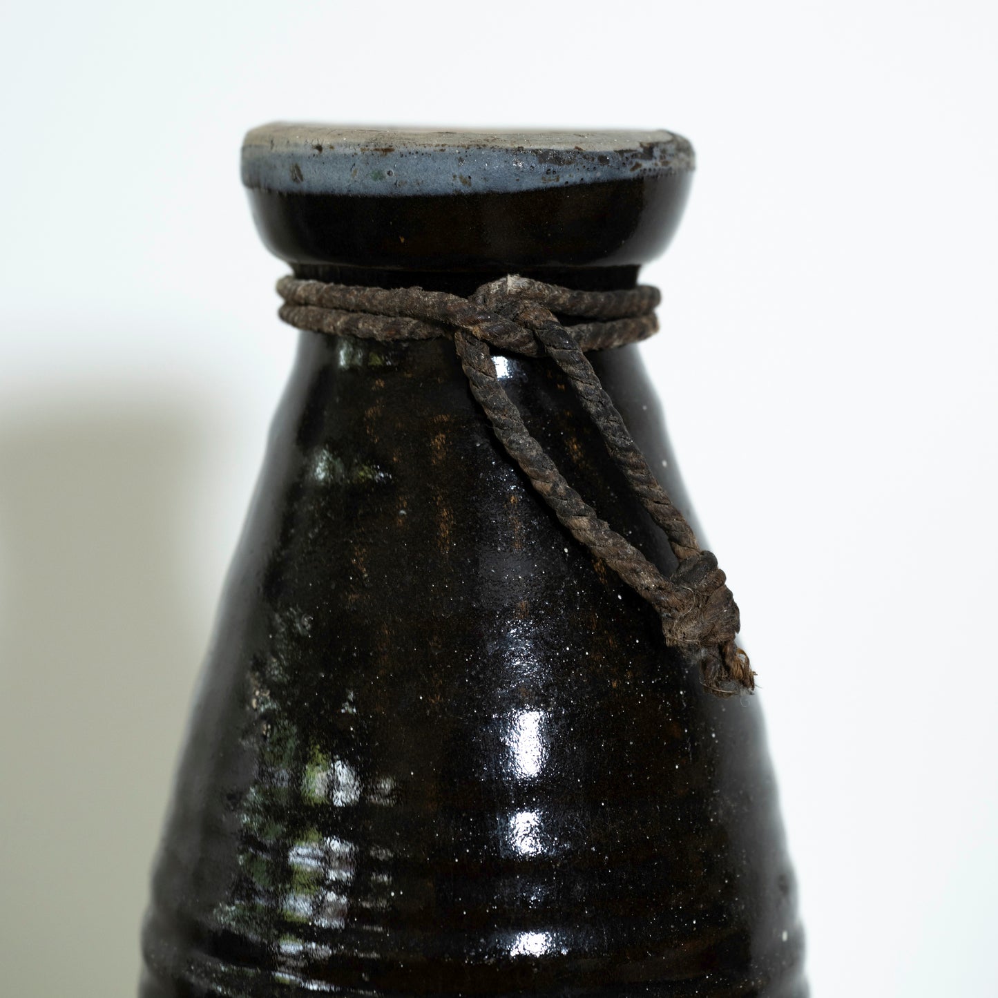 Black ceramic bottle with a rope tie on a white background
