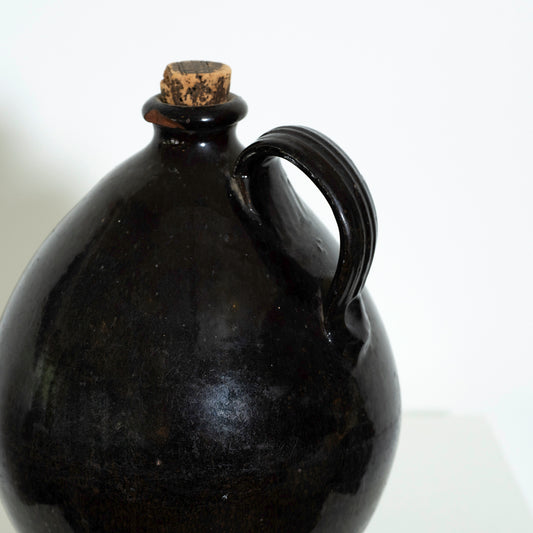 Black ceramic jug with a cork stopper on a white background