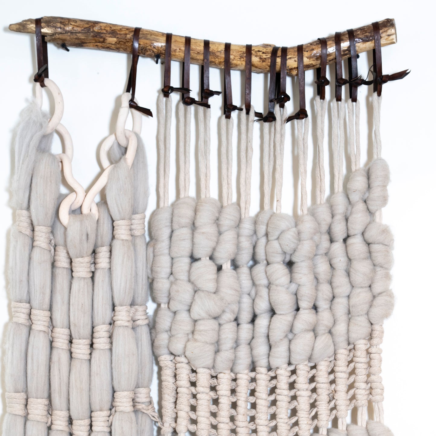 Textured fabric hanging from a wooden rod with hooks on a white background