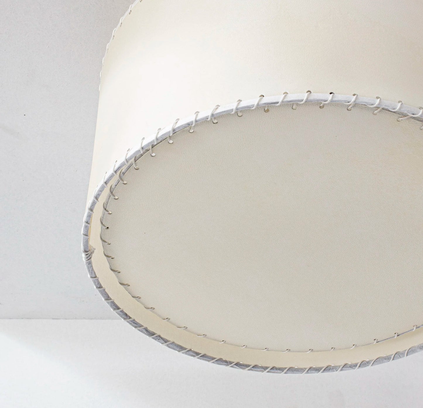 Cream-colored parchment flushmount with cylindrical lampshade featuring textured finish and silver-toned stitched trim