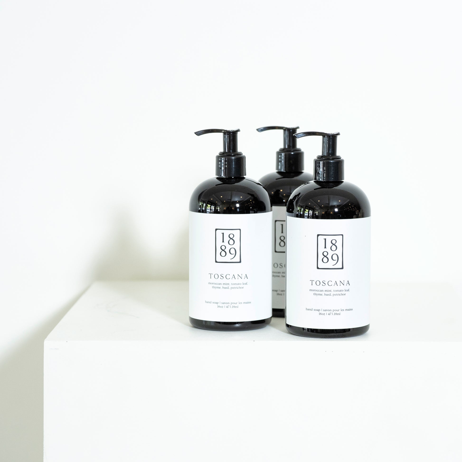 Three black bottles with white labels on a white background