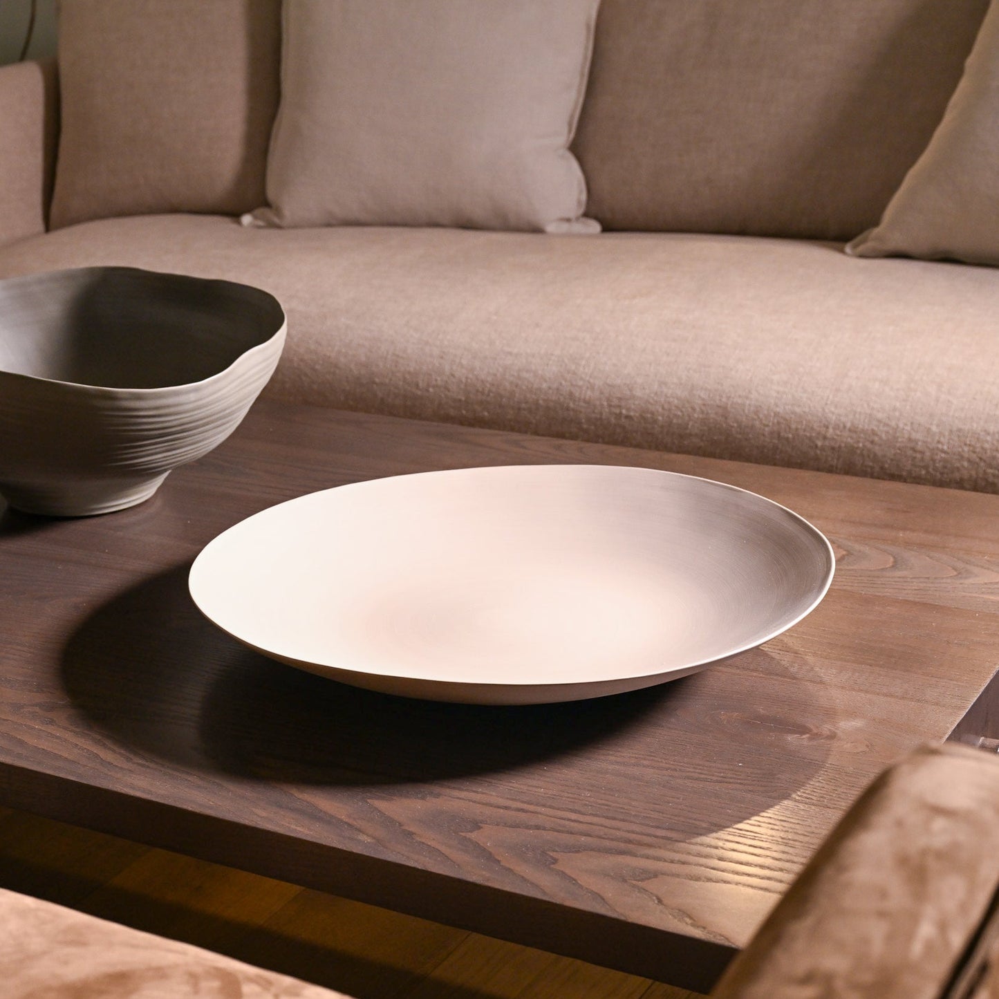 Shell plate large light brown minimal white ceramic bowl with smooth curved rim on dark wood table