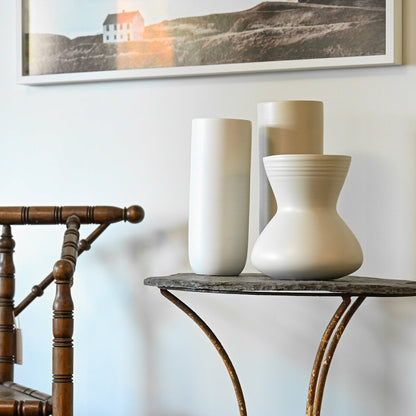 Cream-colored ceramic vases with smooth minimalist design on dark stone tabletop for giare small linen collection
