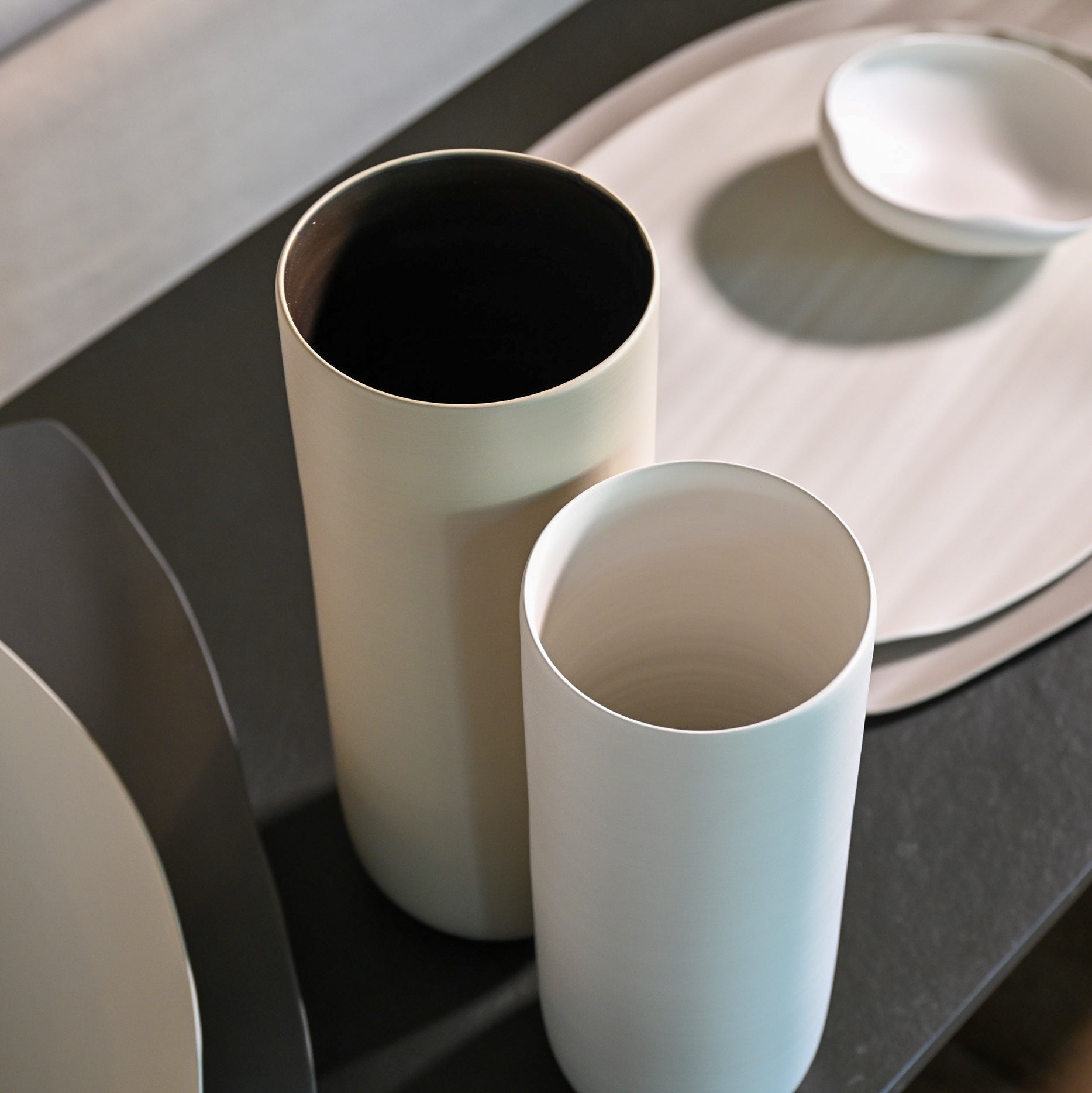 Two minimalist cylindrical ceramic vases canna wide small white in creamy off-white and soft pale blue with dark interiors