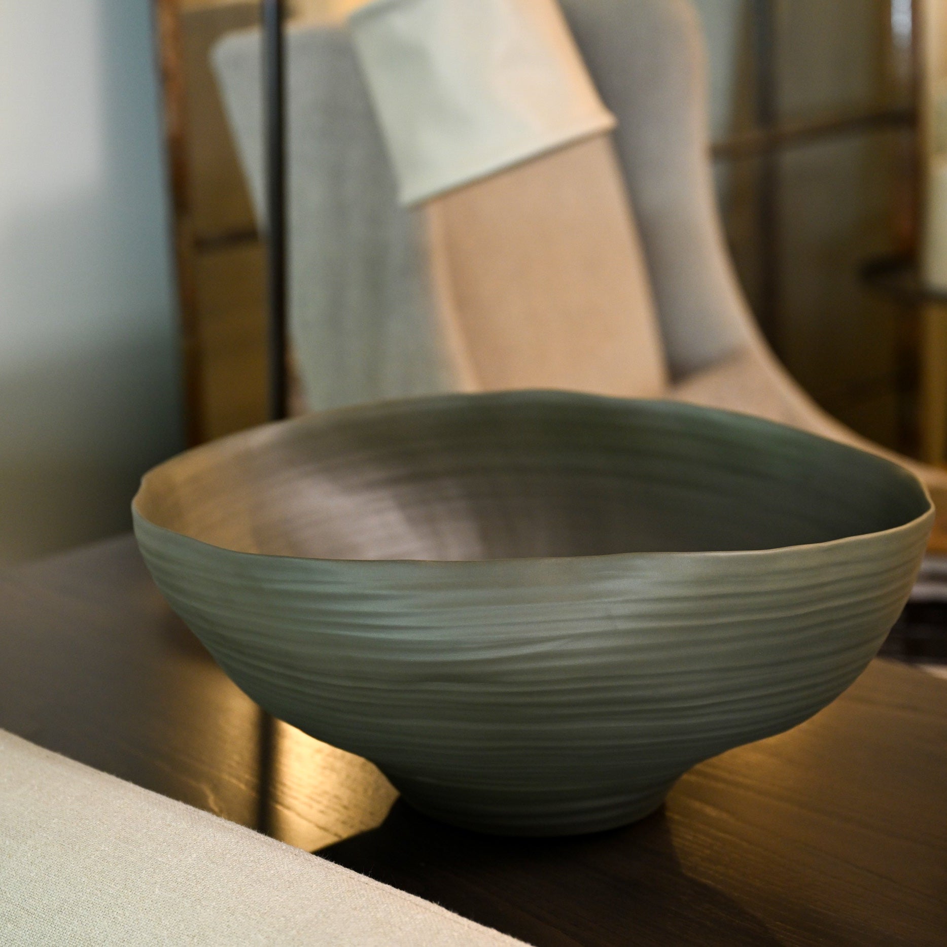 A sleek matte sage green ceramic bowl with subtle horizontal ridges and a gently flared rim called Fonte medium moss