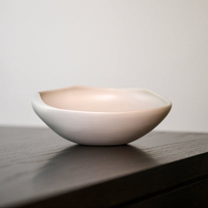 A smooth matte-finished ceramic bowl conchiglia small white with a soft blush pink interior and subtle white exterior
