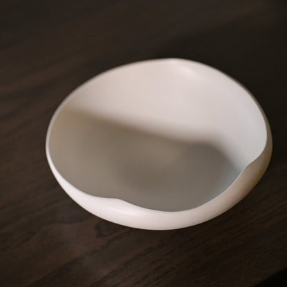 A minimalist white ceramic bowl conchiglia small with a smooth irregular rim and subtle glossy finish