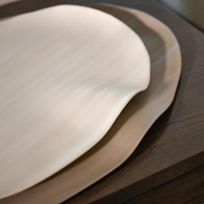 Cream-colored smooth ceramic plate with gently curved edge from leaf large linen collection