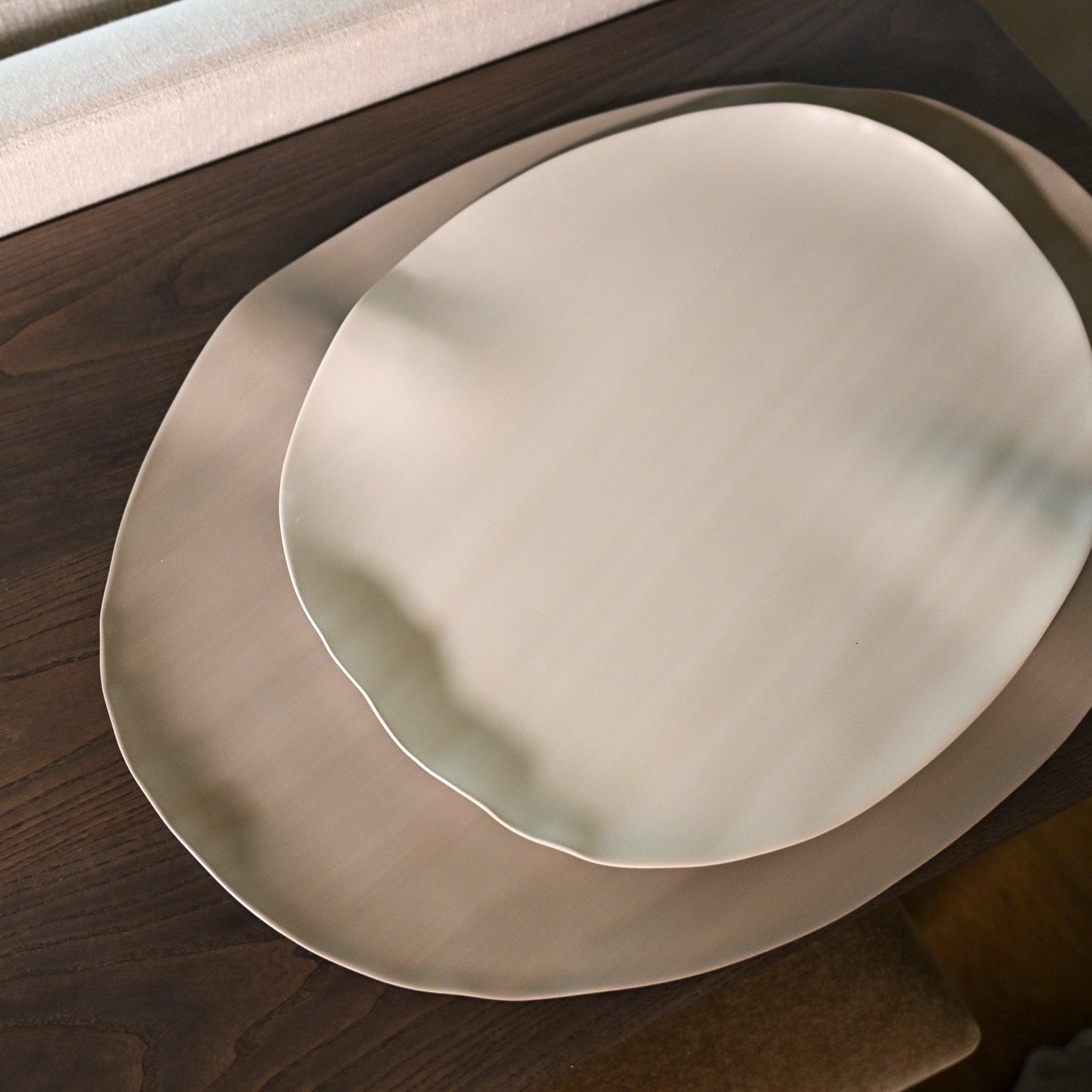 Leaf XLarge light brown off-white ceramic plates with organic irregular edges stacked on dark wooden surface