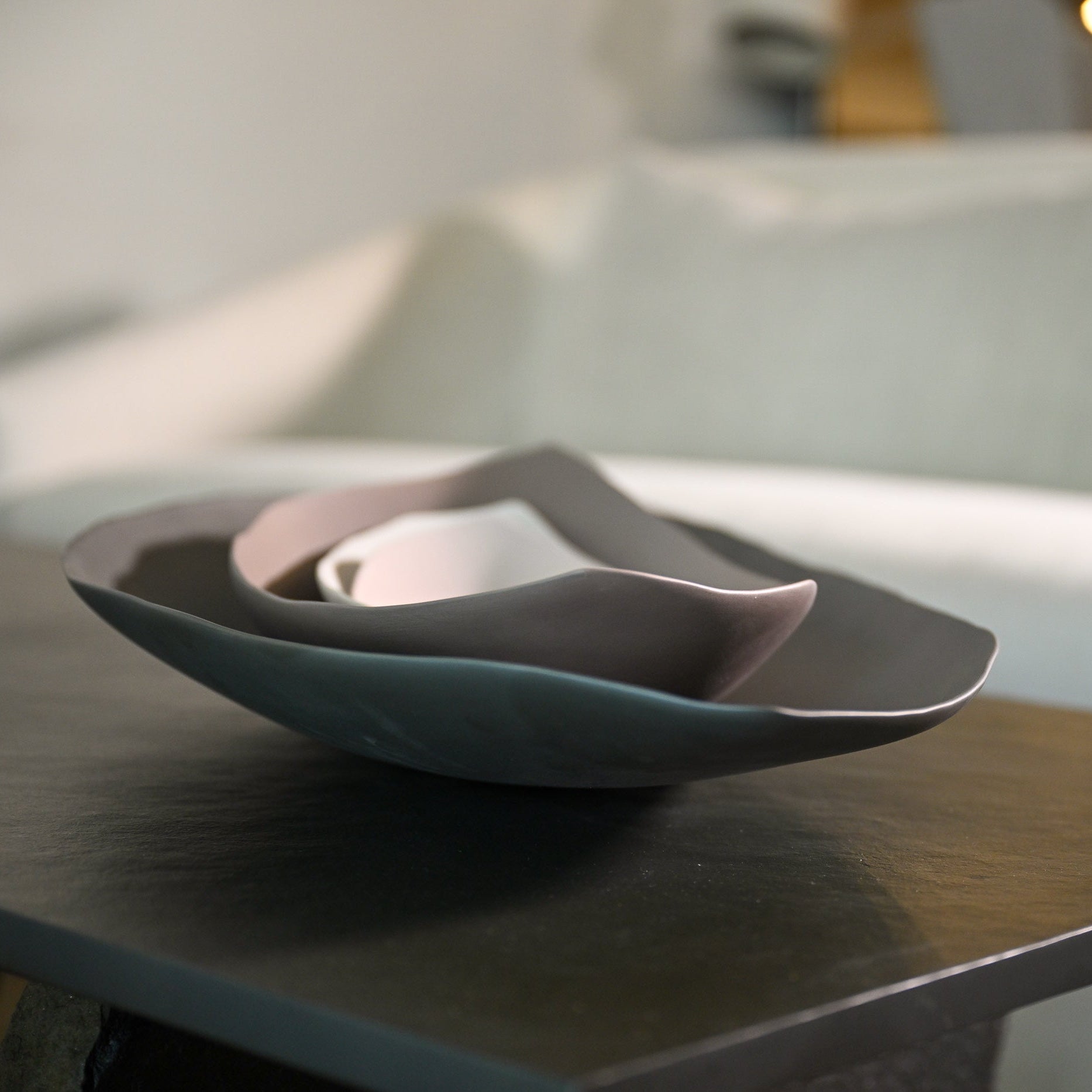 A set of three nested barchetta strette medium ceramic bowls in linen with muted teal dusty rose and white colors