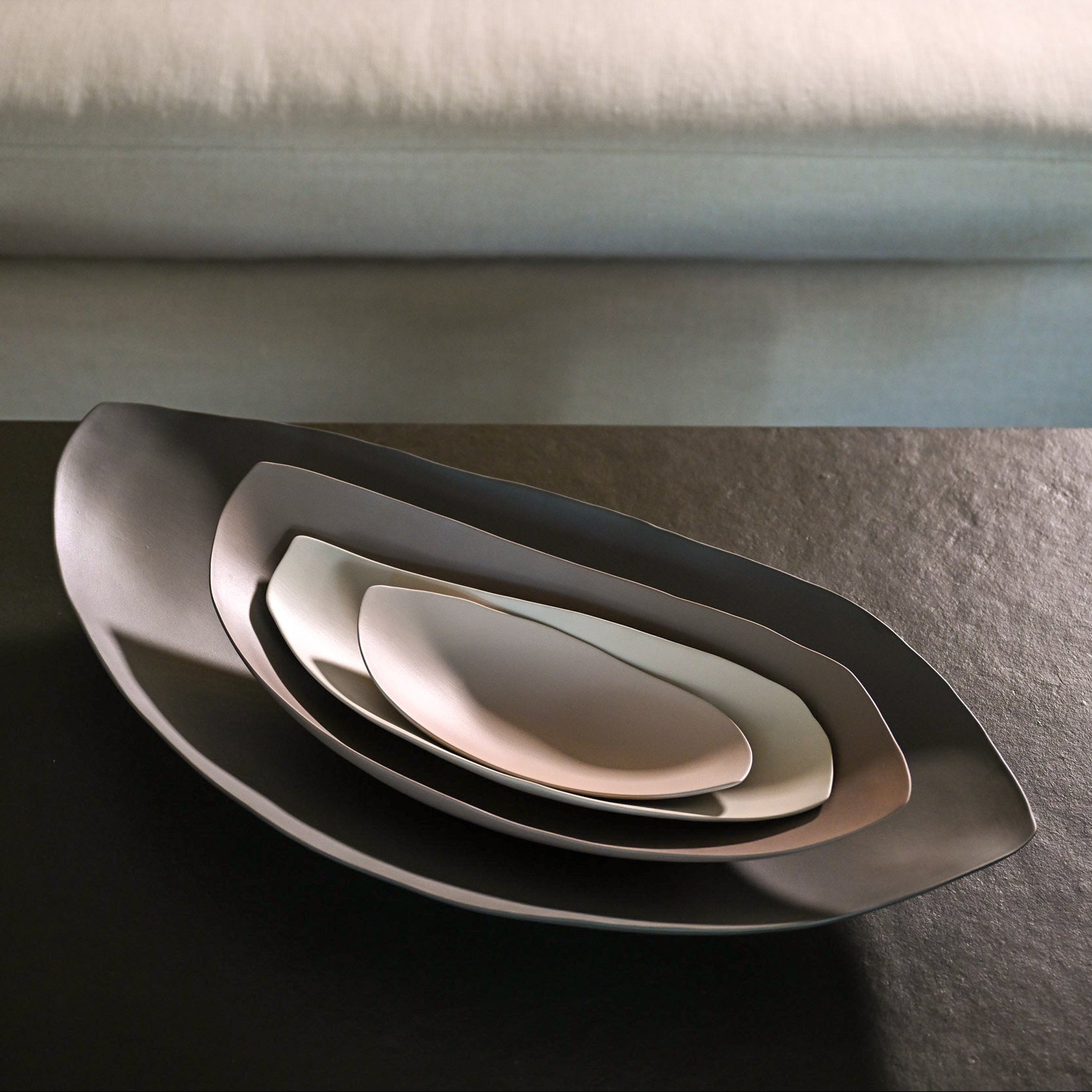 Set of three nested barchetta strette large ceramic plates in matte gray and off-white dark turtledove finish
