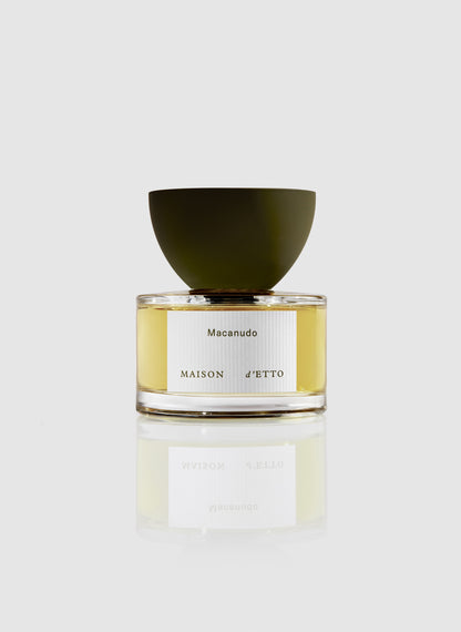 A sleek transparent glass perfume bottle with a matte olive green bowl cap and silver macañudo label by Maison dEtto