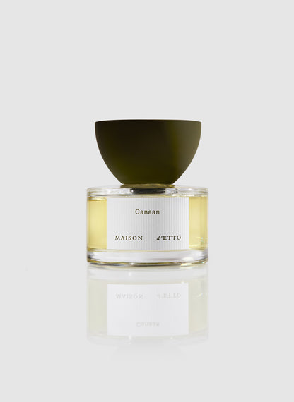 A sleek transparent glass perfume bottle with a matte olive-green cap and minimalist white canaan label by Maison dEtto