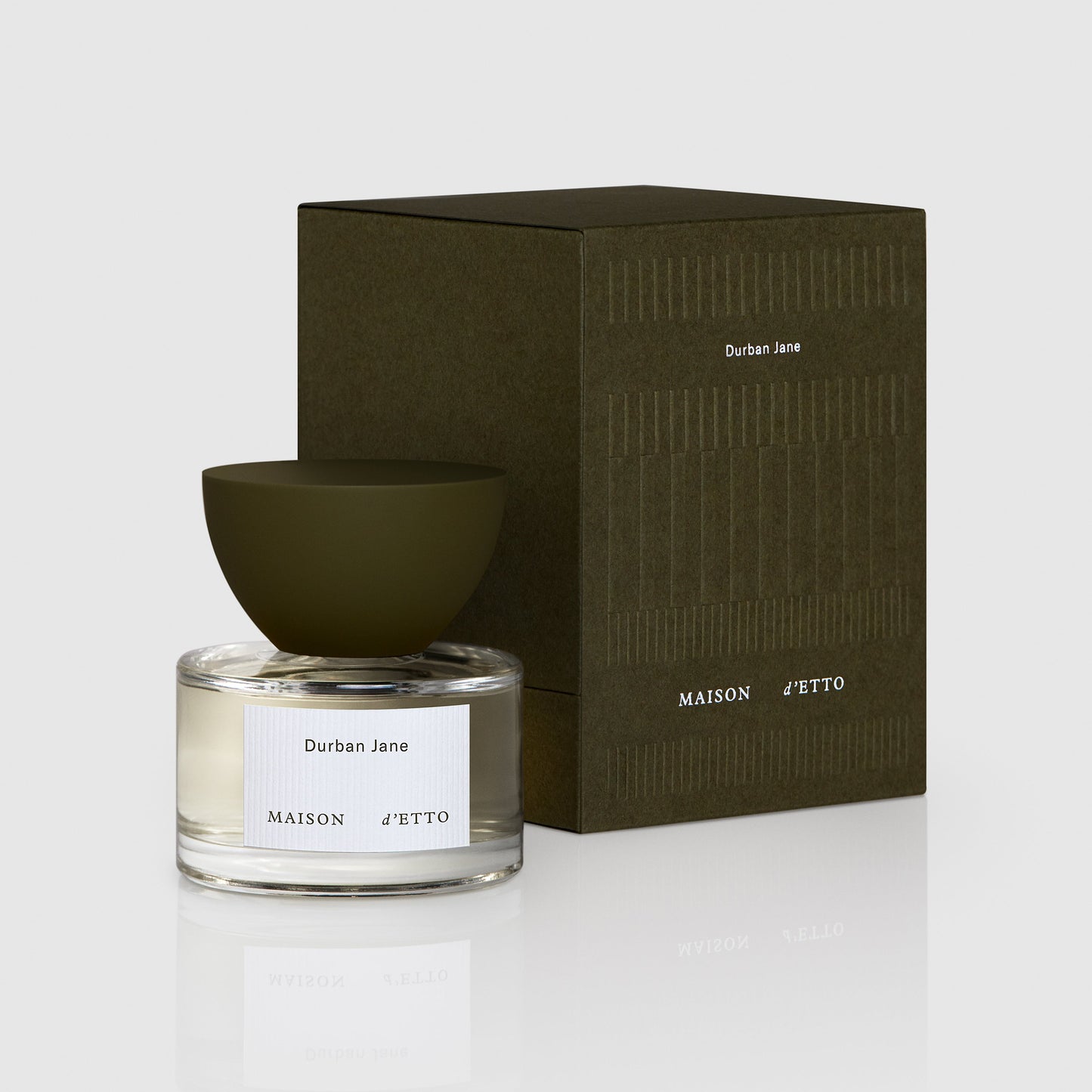 A clear glass fragrance bottle with a matte olive green bowl shaped cap labeled durban jane by maison d etto