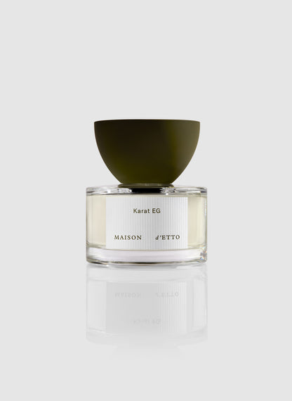 Minimalist glass perfume bottle with matte olive-green bowl-shaped cap and white karat eg label by maison d etto