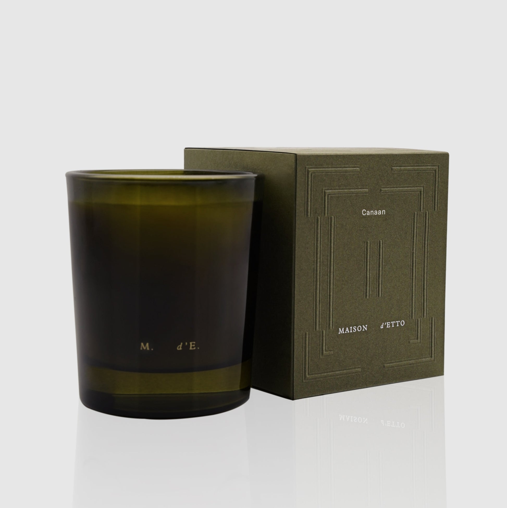 Olive-green glass candle jar with minimalist embossed branding from maison detteo candle canaan collection