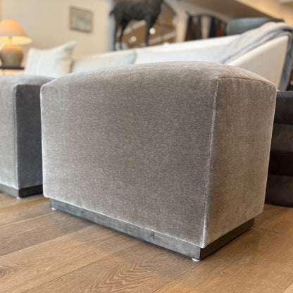 Gray velvet aurora ottoman with square cushioned design and dark wooden base floor model for living room use