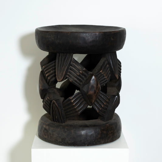 Black stone stool with intricate carvings on a white background
