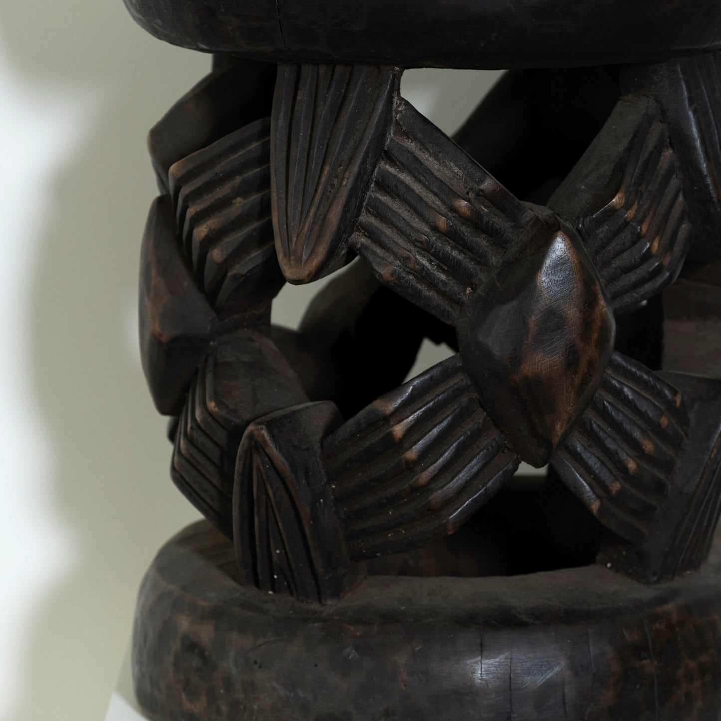 Close-up of a dark brown wooden bracelet with intricate patterns on a light background