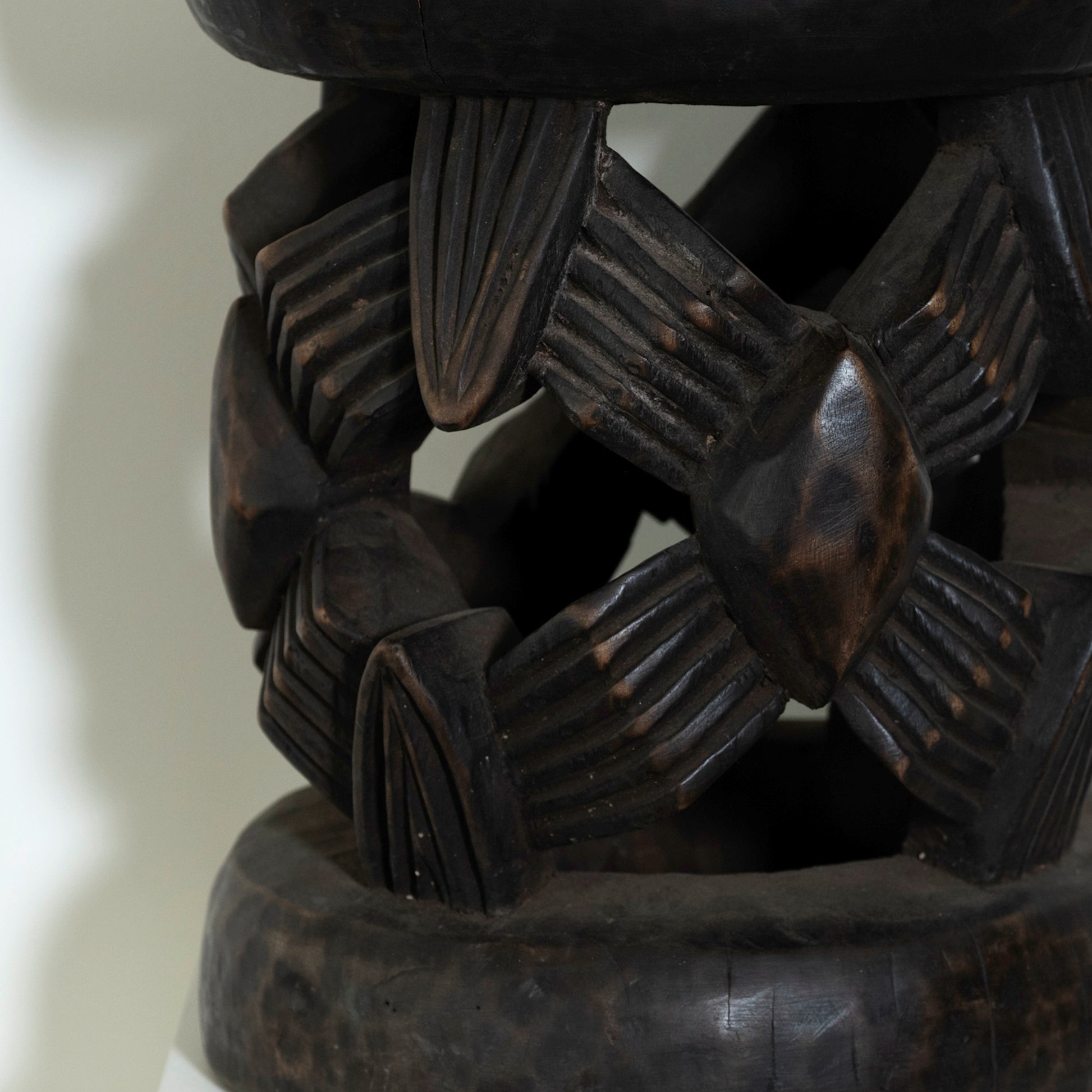 Close-up of a dark brown wooden bracelet with intricate patterns on a light background