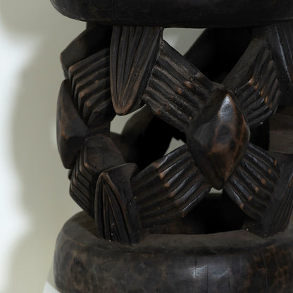 Close-up of a dark brown wooden bracelet with intricate patterns on a light background
