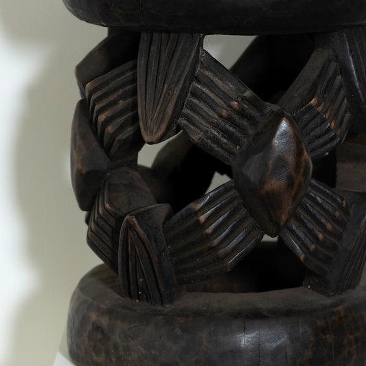 Close-up of a dark brown wooden bracelet with intricate patterns on a light background