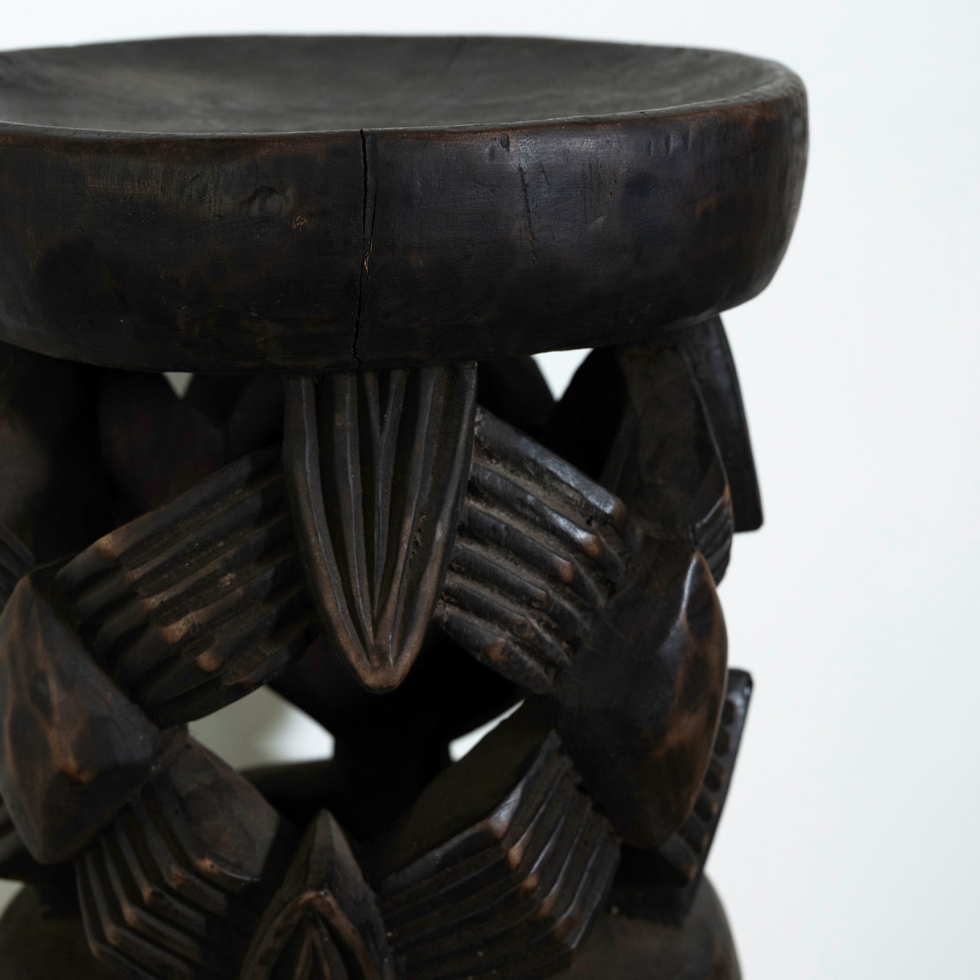 Dark wooden stool with intricate carvings on a white background