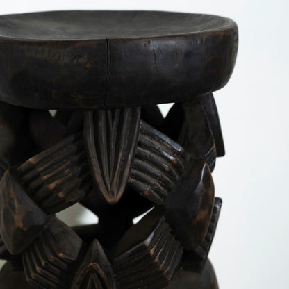 Dark wooden stool with intricate carvings on a white background