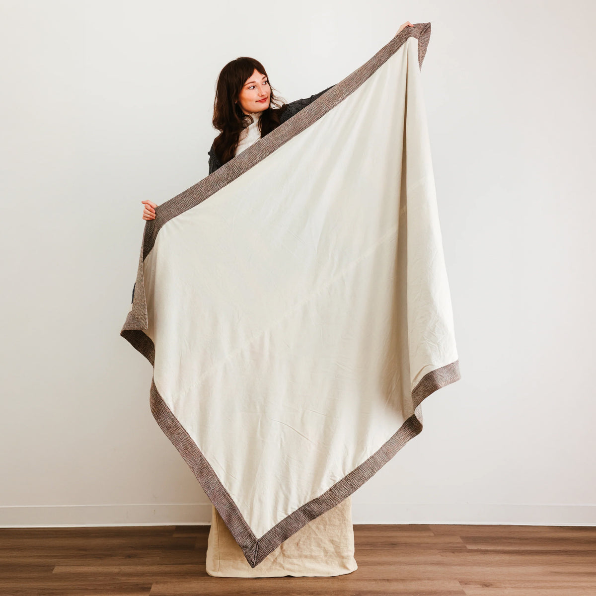 Large cream-colored quilt or blanket with a contrasting brown border.