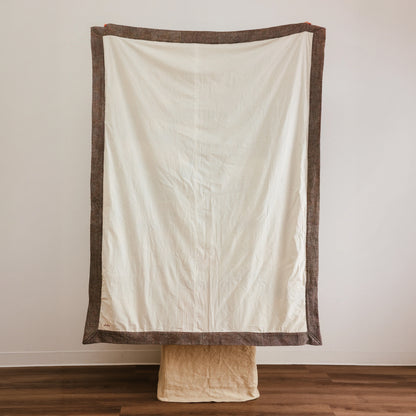An off-white fabric backdrop with a brown border.