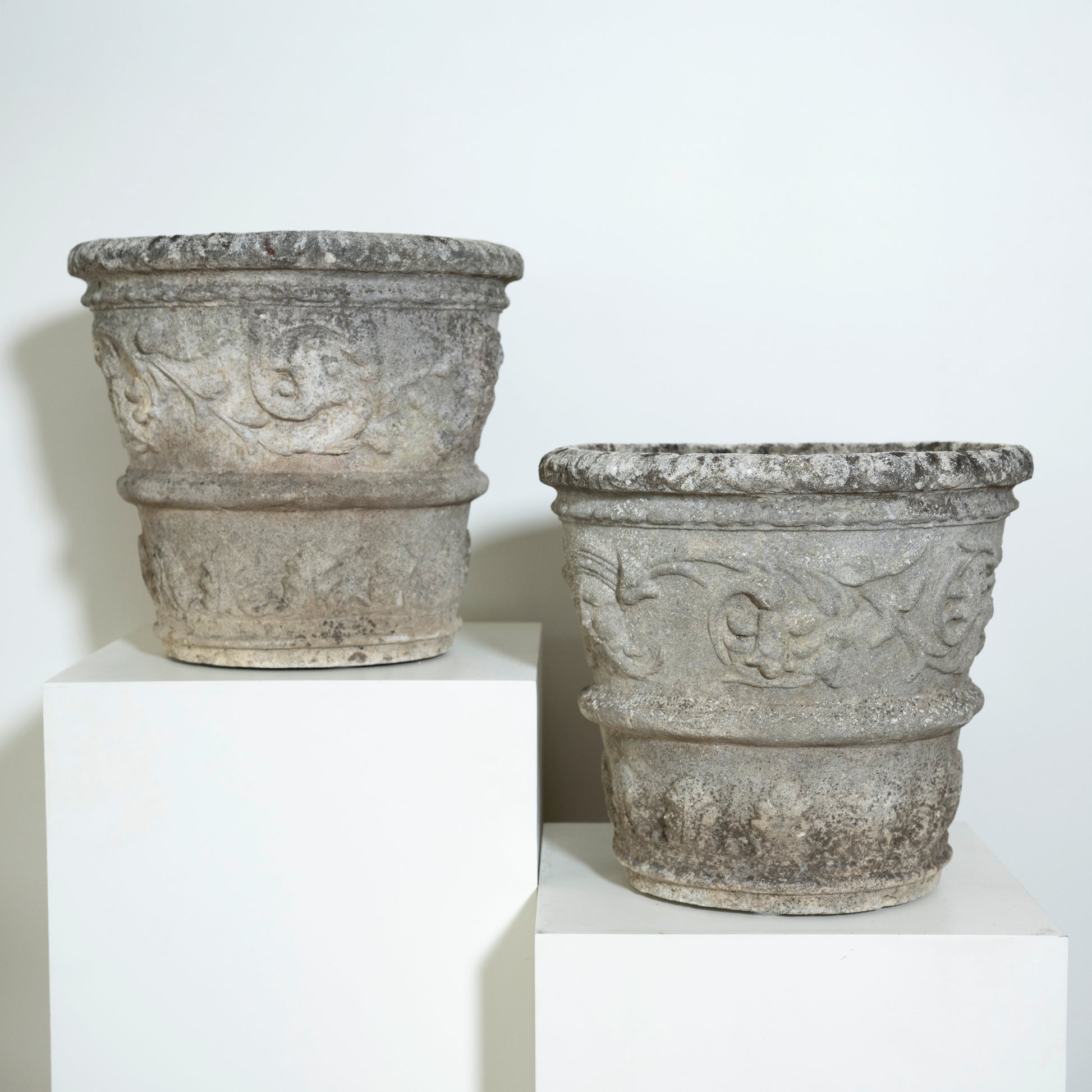 Two stone planters with decorative carvings on a white background