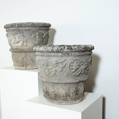 Two decorative stone planters on a white surface with a light gray background