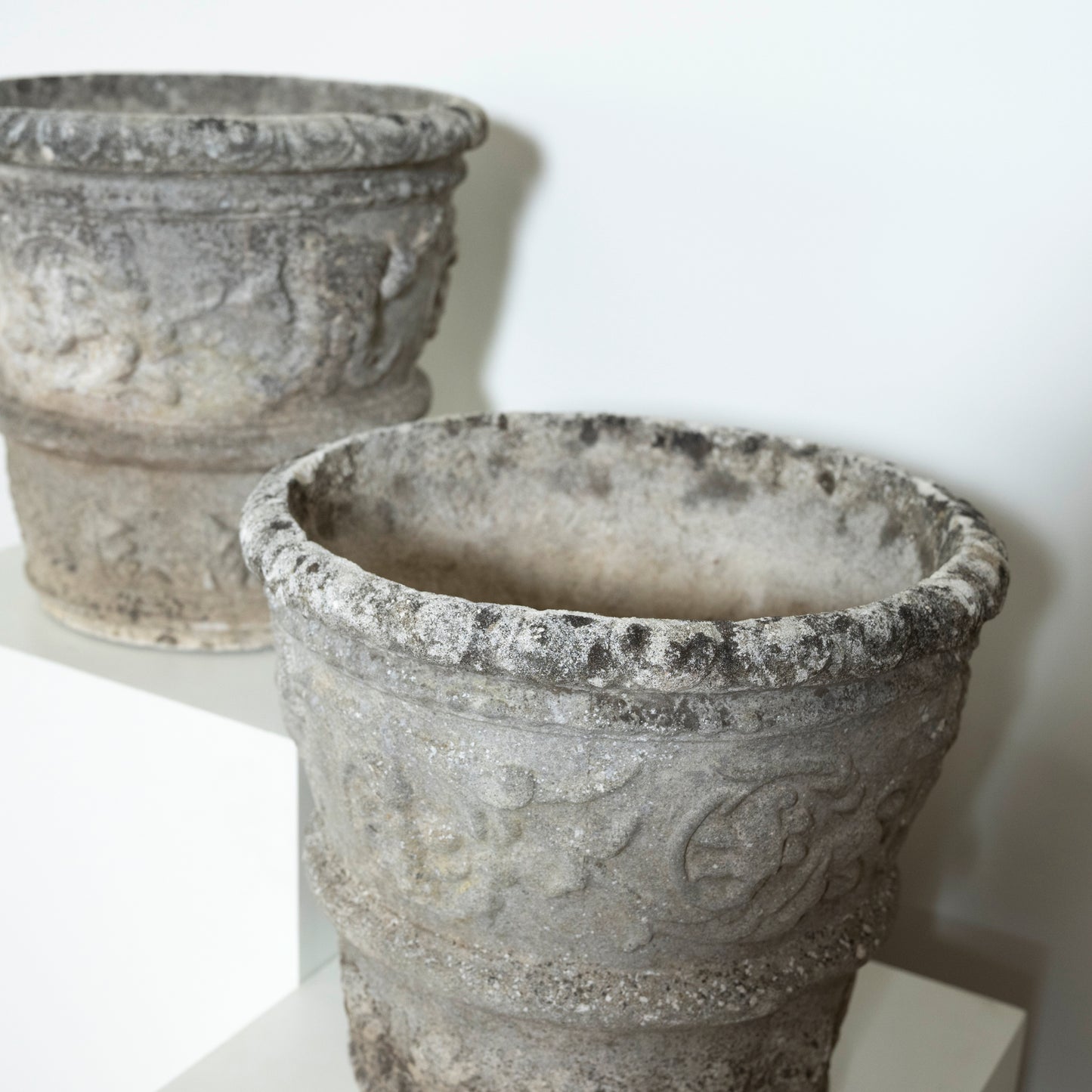 Two stone pots with intricate designs on a white background