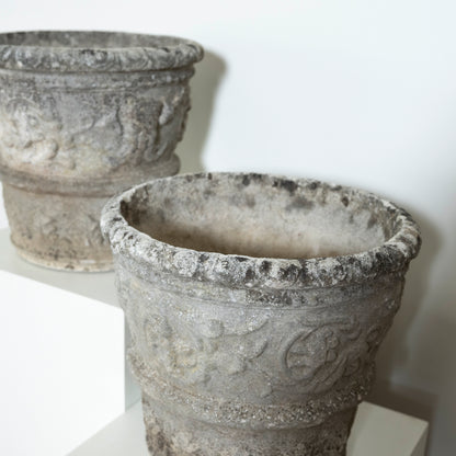 Two stone pots with intricate designs on a white background