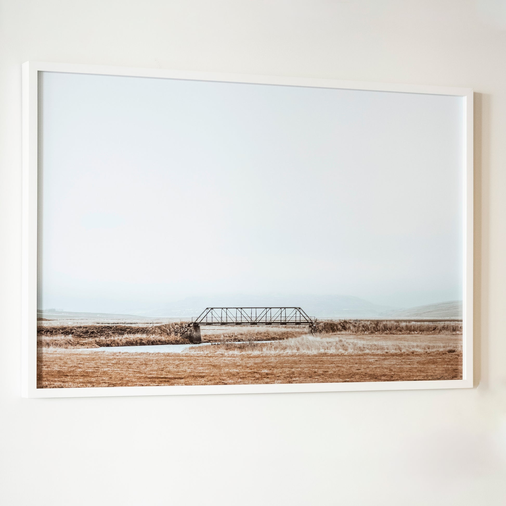 Framed photograph of a bridge over a field on a white wall