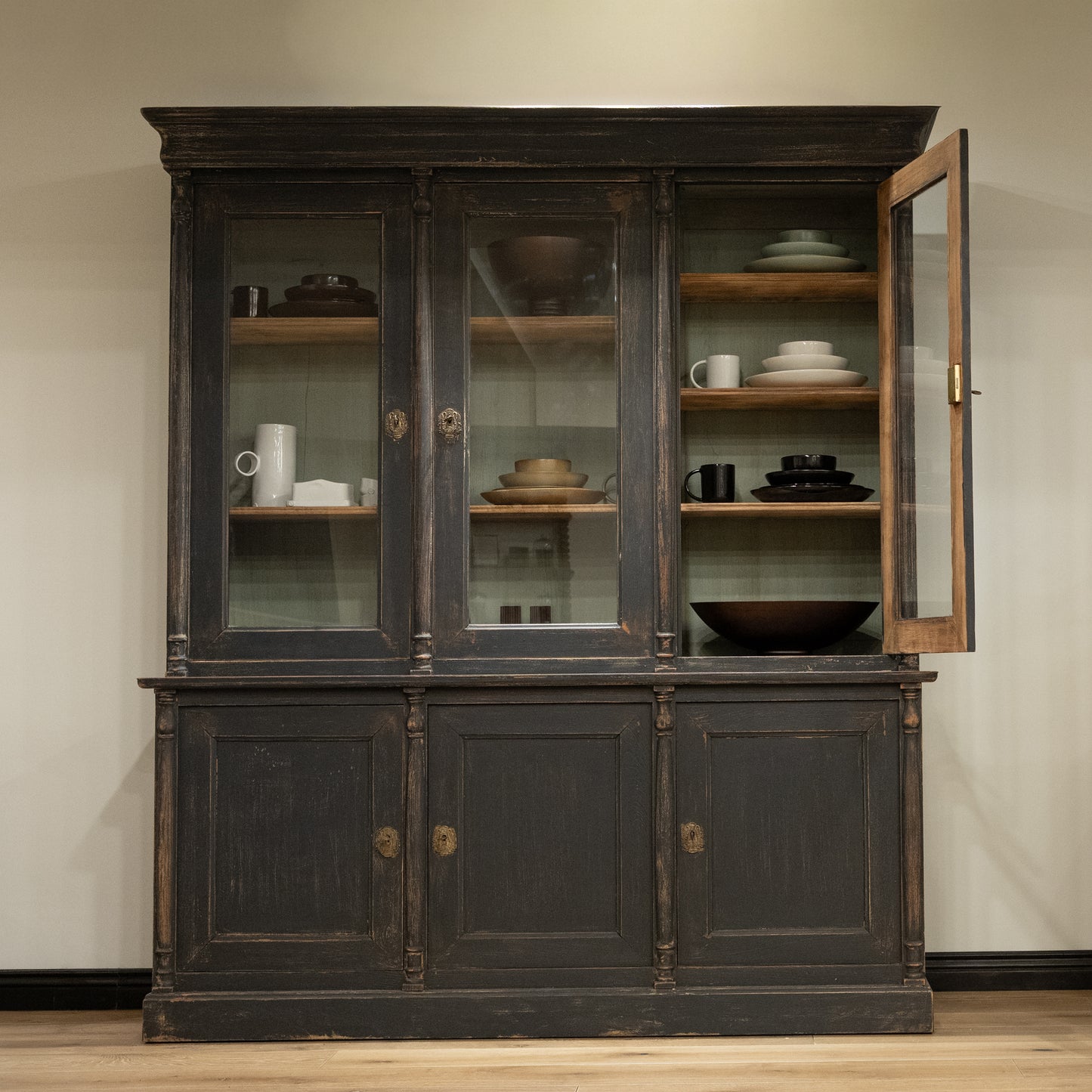 Late 19th century French display cabinet with dark gray distressed wood, glass doors, and brass hardware